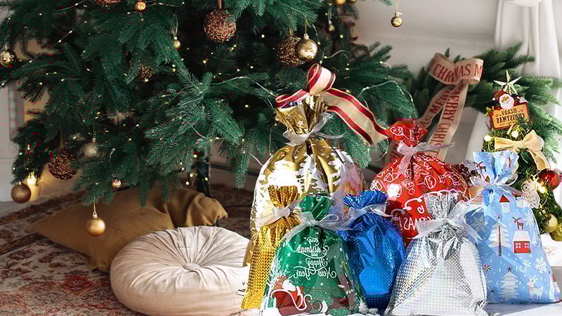 Beautifully arranged metallic drawstring gift bags under a Christmas tree